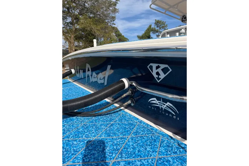 Slide: The Image of 2004 Jupiter 31 Cuddy boat with custom graphics and blue deck, docked outdoors. - 16