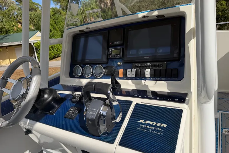Slide: The Image of 2004 Jupiter 31 Cuddy boat dashboard with steering wheel and navigation controls. - 24