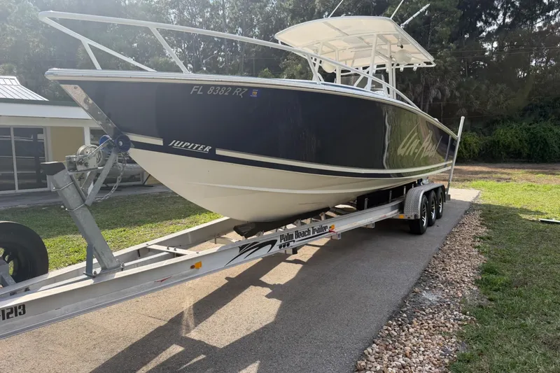 Slide: The Image of 2004 Jupiter 31 Cuddy boat on trailer, parked outdoors in a driveway. - 5