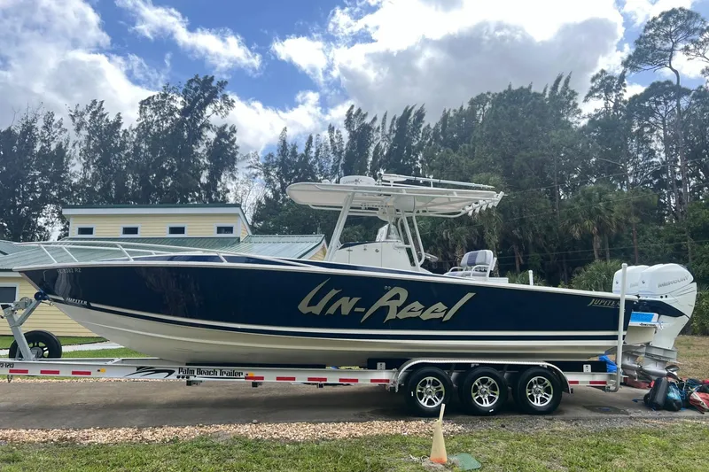 Slide: The Image of 2004 Jupiter 31 Cuddy boat on trailer, labeled "Un-Reel," with trees and buildings in background. - 6
