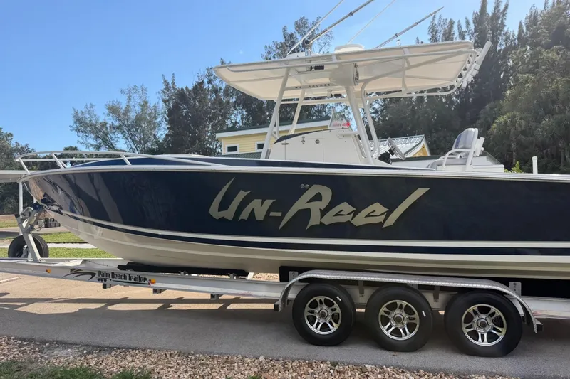 Slide: The Image of 2004 Jupiter 31 Cuddy boat on trailer, named "Un-Reel," parked outdoors. - 7