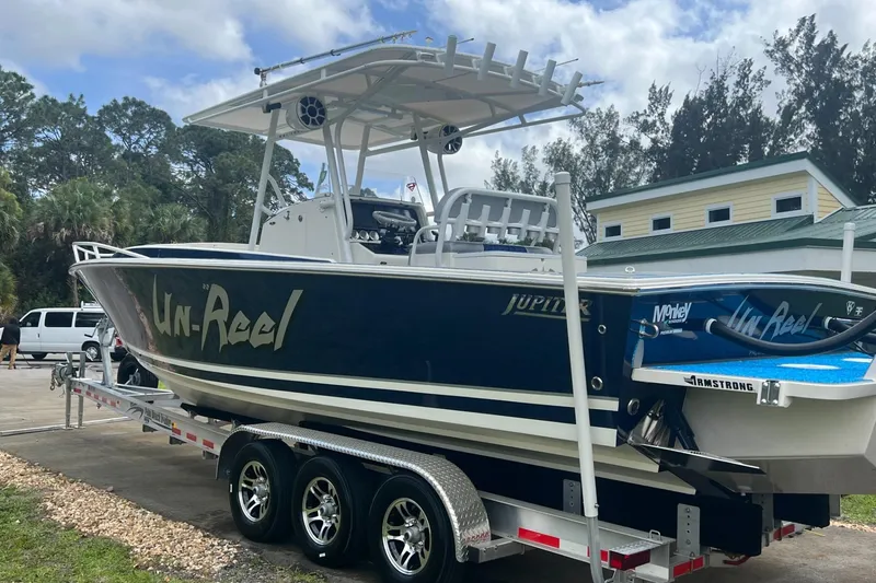 Slide: The Image of 2004 Jupiter 31 Cuddy boat on trailer, featuring "Un-Reel" branding, parked outdoors. - 8