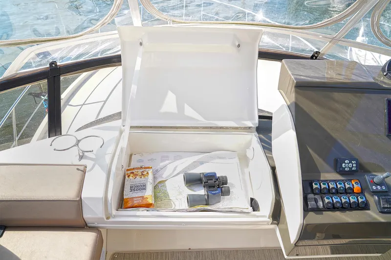 Slide: The Image of Open storage compartment on 2020 Carver C40 yacht with binoculars and maps. - 11