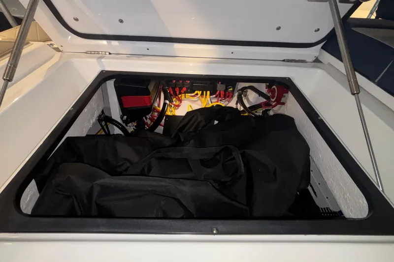 Slide: The Image of Open storage compartment of 2026 Monterey Elite 27 OB boat, showing wiring and equipment. - 24