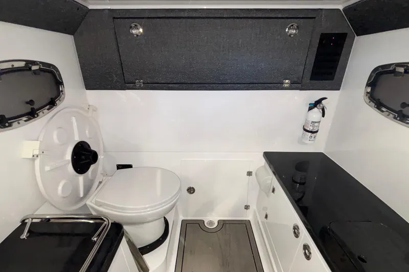 Slide: The Image of Interior of 2026 Monterey Elite 27 OB boat bathroom with toilet and storage. - 55