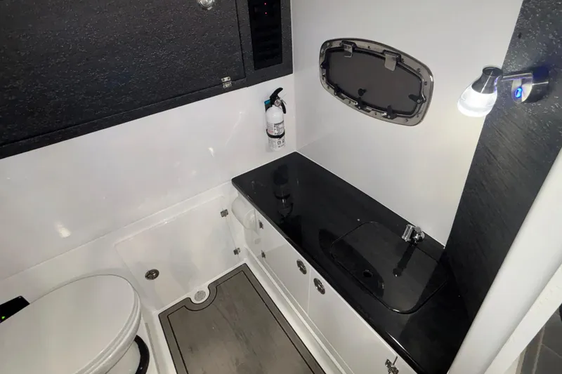 Slide: The Image of 2026 Monterey Elite 27 OB boat bathroom with sleek black countertop and modern fixtures. - 56