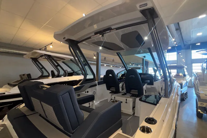 Slide: The Image of 2026 Monterey Elite 27 OB boat interior with modern seating and sleek design in showroom. - 7
