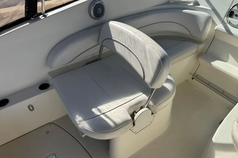 Slide: The Image of 2009 Bayliner 265 SB boat interior with white cushioned seating and cup holders. - 18