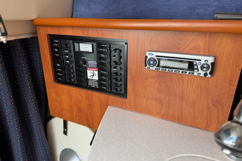 Slide: The Image of 2009 Bayliner 265 SB control panel and stereo on wood finish dashboard. - 26