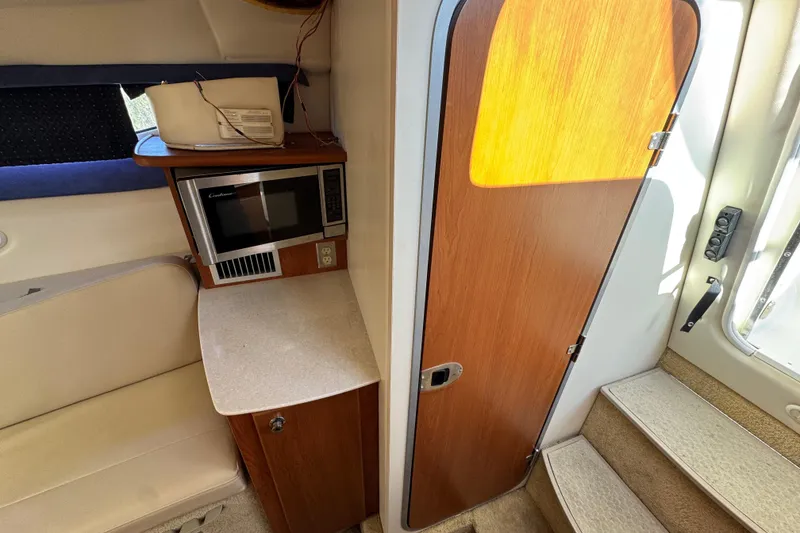 Slide: The Image of 2009 Bayliner 265 SB interior with microwave, seating, and wooden door. - 29