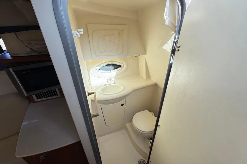 Slide: The Image of 2009 Bayliner 265 SB boat bathroom with sink, toilet, and porthole window. - 30