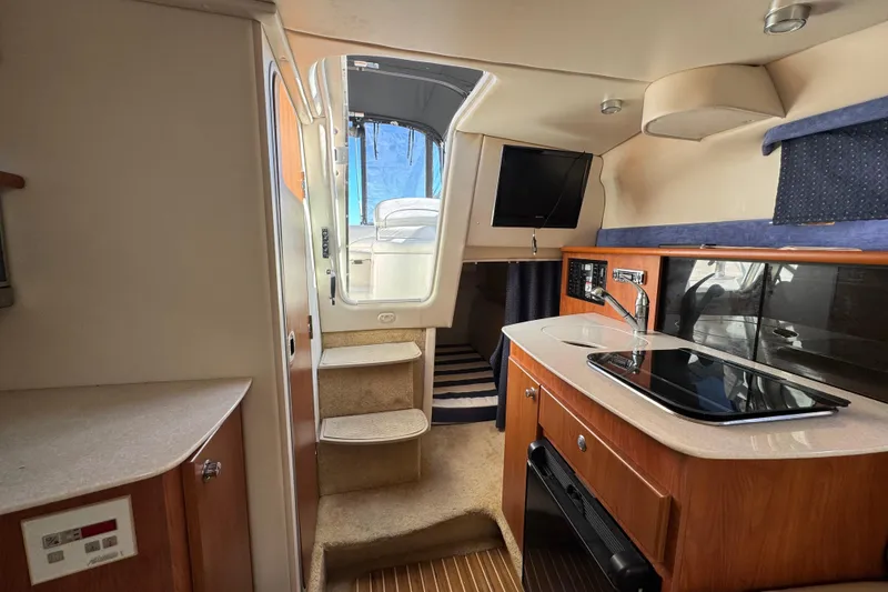 Slide: The Image of 2009 Bayliner 265 SB interior with kitchenette, stairs, and TV. - 31