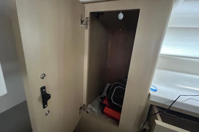 Slide: The Image of Open cabinet inside 2023 Regal 38 FXO boat, showing storage space and items. - 109