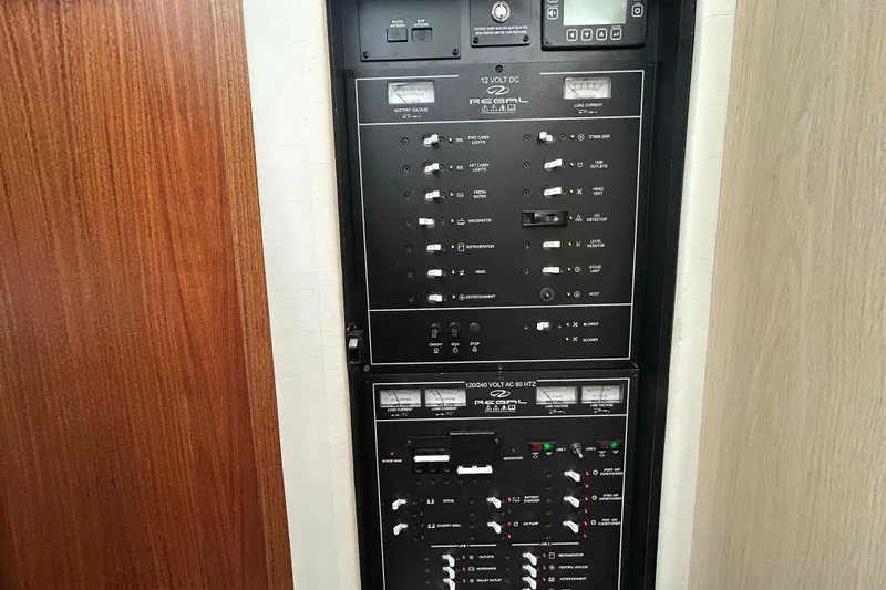 Slide: The Image of Electrical control panel on a 2023 Regal 38 FXO boat, featuring various switches and meters. - 126