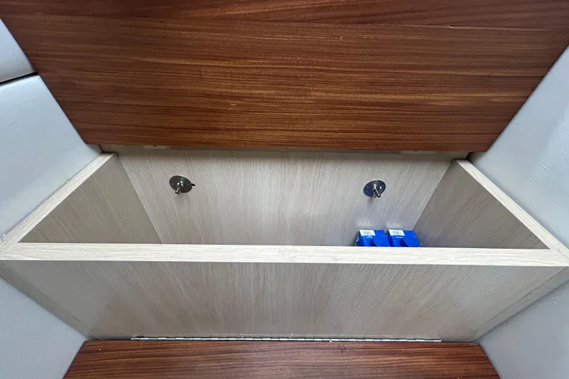 Slide: The Image of Storage compartment in 2023 Regal 38 FXO boat with wooden finish and blue items inside. - 129