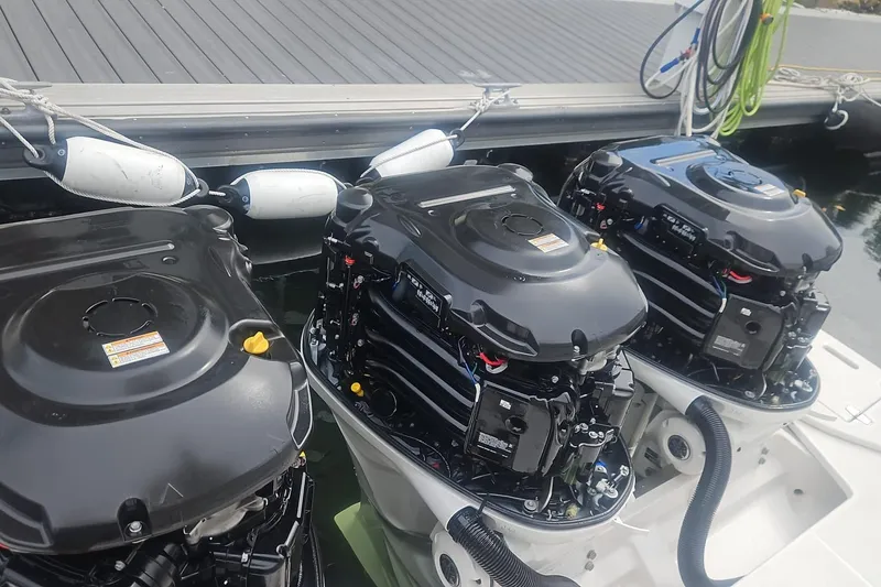 Slide: The Image of Triple outboard engines on a 2023 Regal 38 FXO boat docked at a marina. - 130