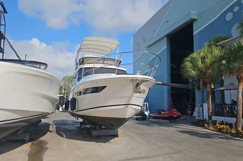 Slide: The Image of 2023 Regal 38 FXO yacht docked near a large blue building under a clear sky. - 3