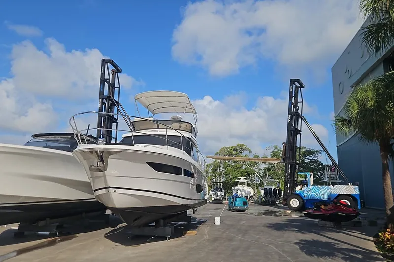Slide: The Image of 2023 Regal 38 FXO yacht in a marina, surrounded by equipment and clear skies. - 4