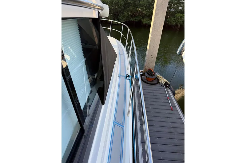 Slide: The Image of 2023 Regal 38 FXO boat deck with stainless steel railing, docked on calm water. - 48