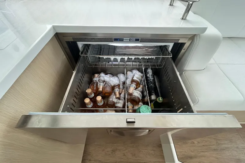 Slide: The Image of Open cooler drawer on 2023 Regal 38 FXO yacht, filled with ice and bottled drinks. - 83