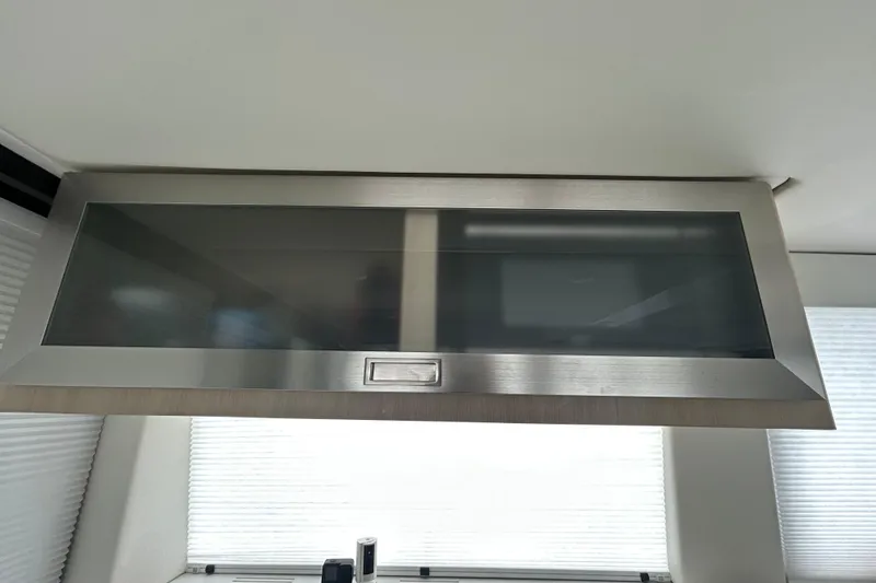 Slide: The Image of Modern kitchen cabinet in 2023 Regal 38 FXO yacht interior, featuring sleek glass and metal design. - 87