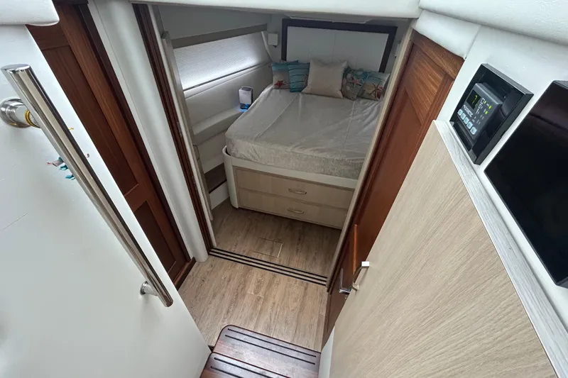 Slide: The Image of 2023 Regal 38 FXO cabin interior with bed, wooden flooring, and control panel. - 92
