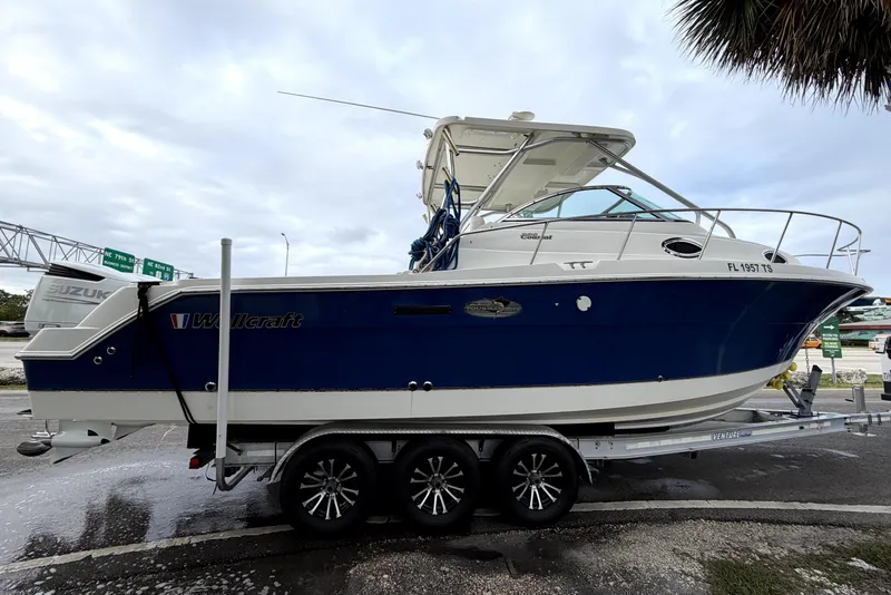 Slide: The Image of 2001 Wellcraft 290 Coastal boat on trailer, blue and white design, parked outdoors. - 15