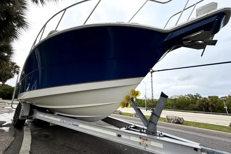 Slide: The Image of 2001 Wellcraft 290 Coastal boat on trailer, blue and white hull, parked roadside. - 17