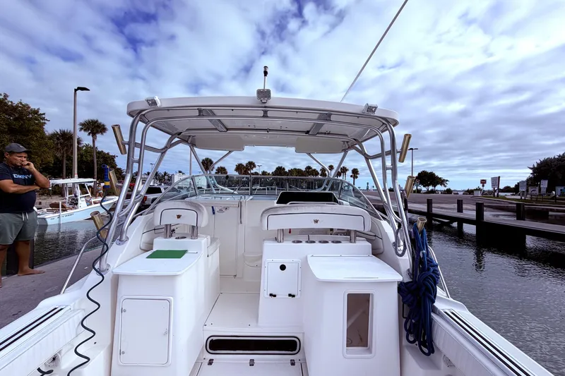 Slide: The Image of 2001 Wellcraft 290 Coastal boat docked, featuring spacious deck and seating under cloudy sky. - 31