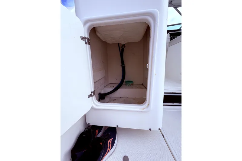 Slide: The Image of Open storage compartment on 2001 Wellcraft 290 Coastal boat, showing interior space and hose. - 44