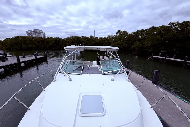 Slide: The Image of 2001 Wellcraft 290 Coastal boat docked near lush greenery and urban skyline. - 51