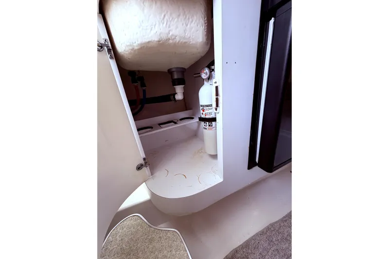 Slide: The Image of 2001 Wellcraft 290 Coastal interior showing storage with fire extinguisher and plumbing. - 95