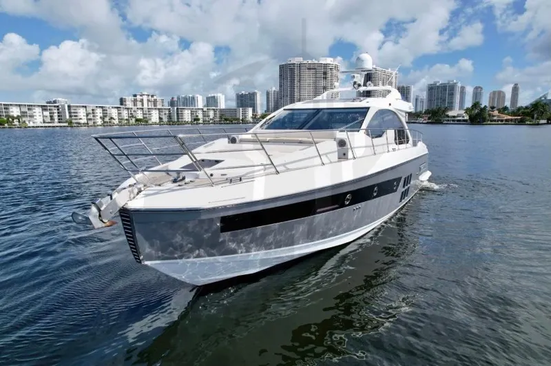 Slide: The Image of 2015 Azimut 55S yacht cruising on a sunny day with city skyline backdrop. - 2