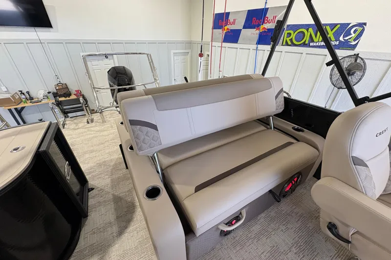 Slide: The Image of 2025 Crest Classic 220 boat interior with beige seating and cup holders in a showroom. - 11