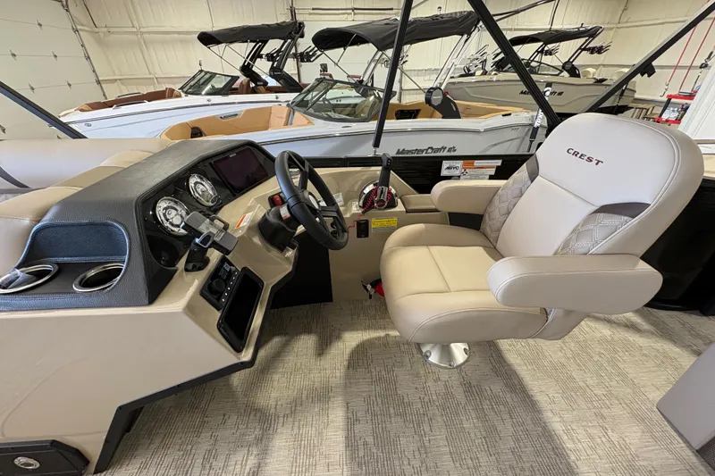 Slide: The Image of 2025 Crest Classic 220 boat interior with steering wheel and captain's chair in showroom. - 16