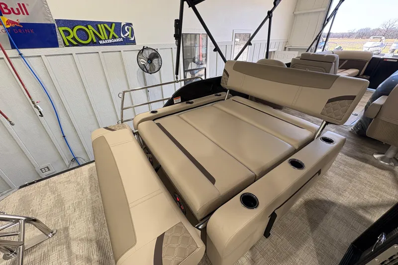 Slide: The Image of 2025 Crest Classic 220 boat interior with beige seating and cup holders in a showroom. - 22