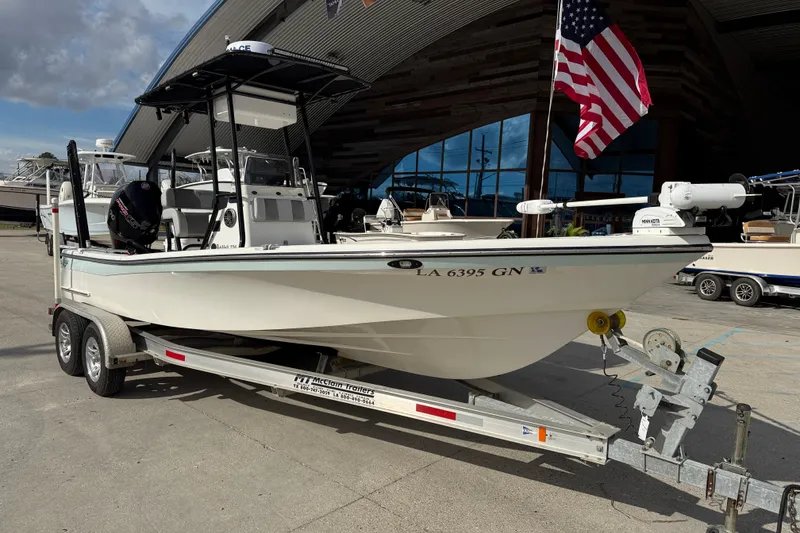 Slide: The Image of 2009 BlackJack 224 boat on trailer, displayed outdoors with American flag. - 2