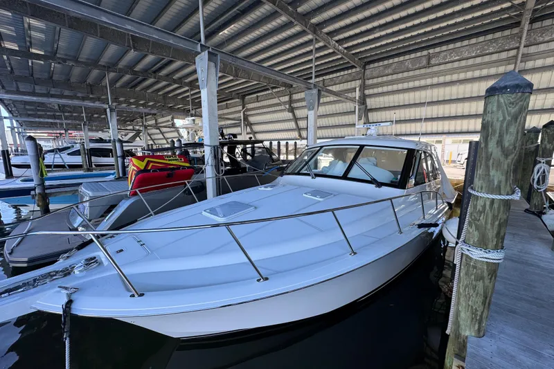 Slide: The Image of 2013 Cabo 44 Hardtop Express yacht docked in a covered marina. - 21