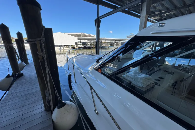 Slide: The Image of 2013 Cabo 44 Hardtop Express yacht docked in a marina under a covered structure. - 25