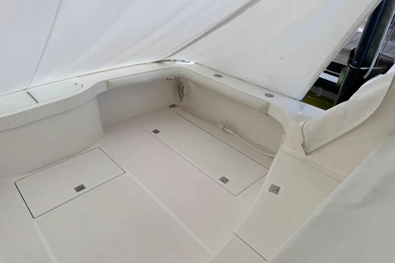 Slide: The Image of 2013 Cabo 44 Hardtop Express boat interior with white seating and storage compartments. - 32