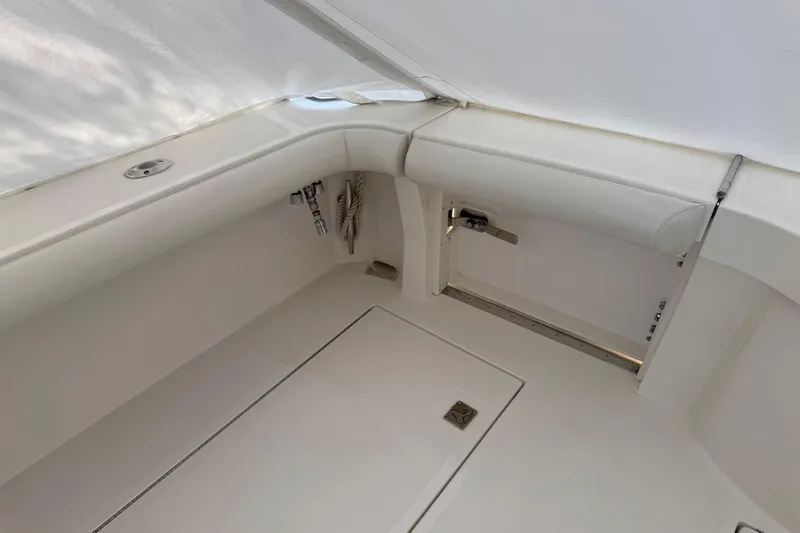 Slide: The Image of Interior view of 2013 Cabo 44 Hardtop Express boat, featuring white seating and storage area. - 34