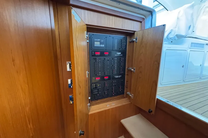 Slide: The Image of Electrical panel inside 2013 Cabo 44 Hardtop Express yacht, featuring wooden cabinetry. - 64