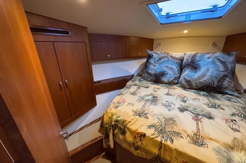 Slide: The Image of 2013 Cabo 44 Hardtop Express cabin with tropical bedding and wooden cabinetry. - 73