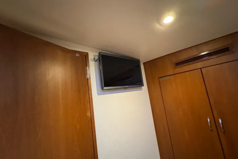 Slide: The Image of Interior of 2013 Cabo 44 Hardtop Express with mounted TV and wooden cabinetry. - 75