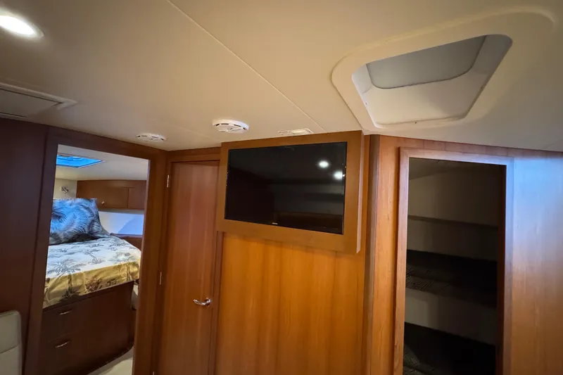 Slide: The Image of 2013 Cabo 44 Hardtop Express interior with TV, bed, and wooden cabinetry. - 76