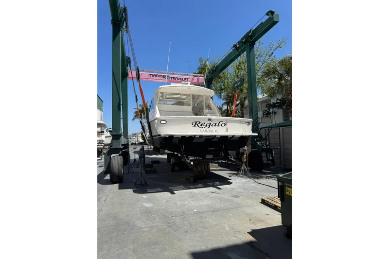 Slide: The Image of 2013 Cabo 44 Hardtop Express boat on lift in marina setting. - 96