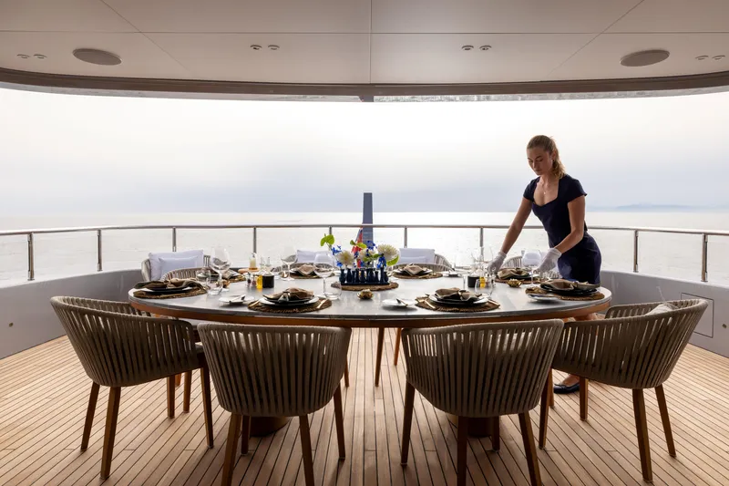 Slide: The Image of 2024 Benetti Oasis 34M yacht dining setup with ocean view and staff preparing table. - 16