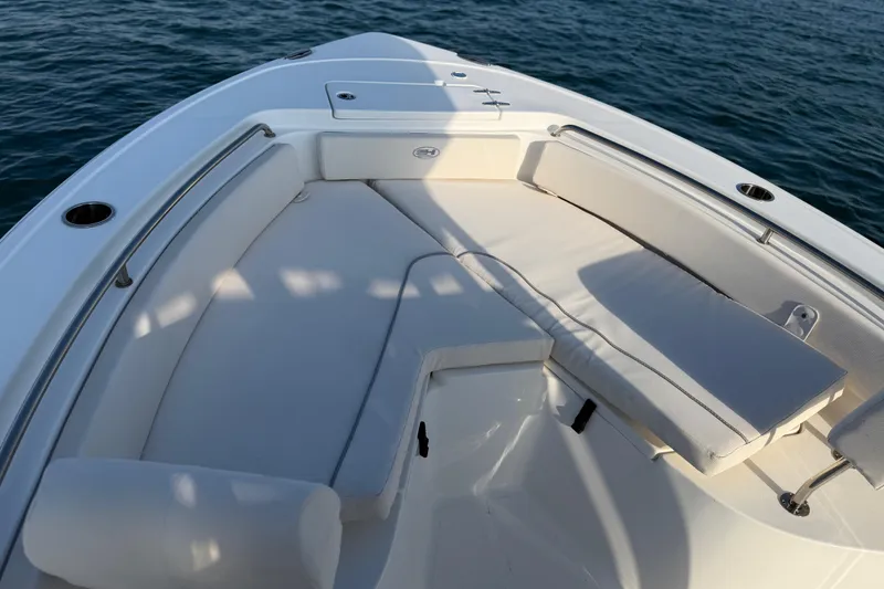 Slide: The Image of 2025 Sea Hunt Ultra 229 boat interior with cushioned seating, on calm water. - 14