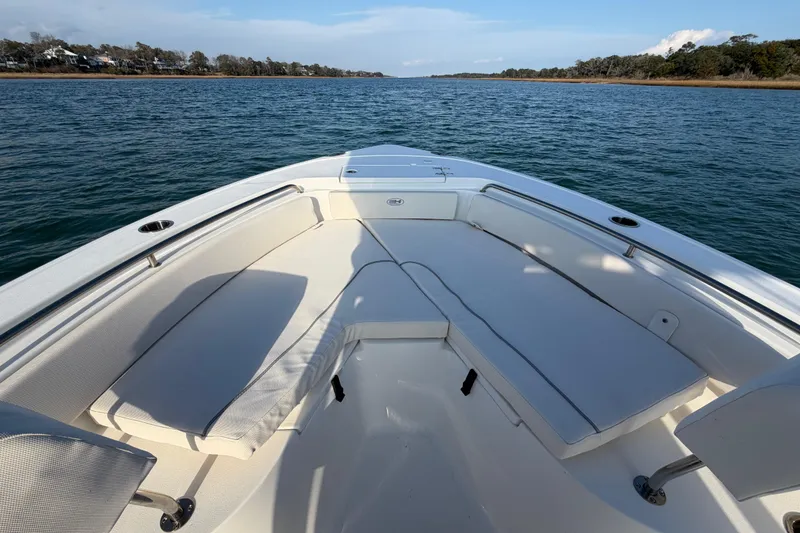 Slide: The Image of 2025 Sea Hunt Ultra 229 boat interior with cushioned seating on calm water. - 15