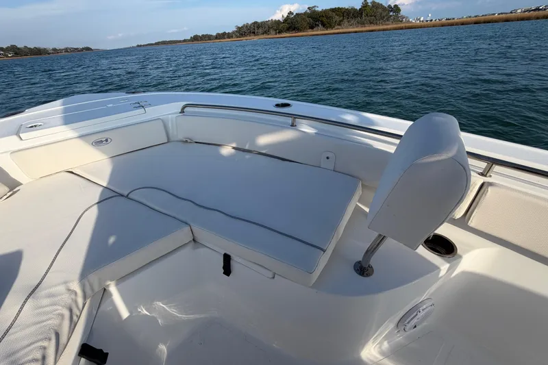 Slide: The Image of 2025 Sea Hunt Ultra 229 boat interior with cushioned seating on calm water. - 17